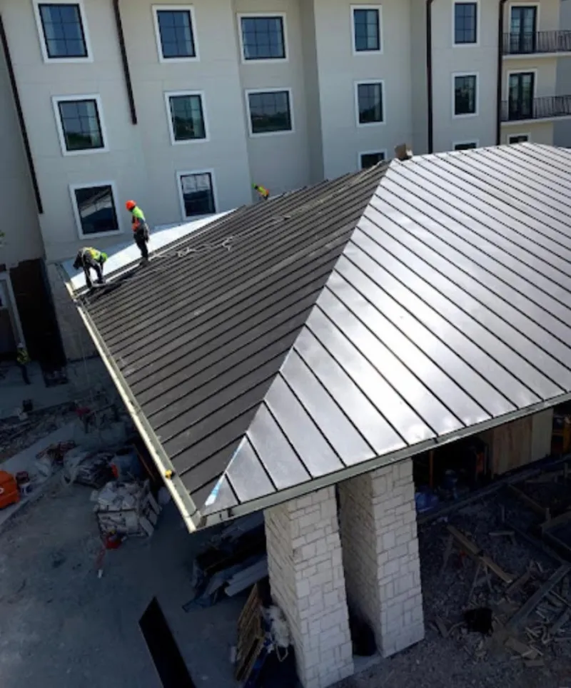 Crew installing standing seam metal roof panels on a commercial project in Millstone